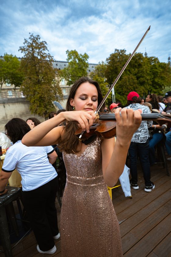 The violinist in a sequinned dress playing on deck