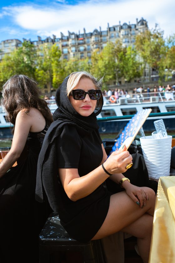 Guest in black with a Céline fan looking out over the Seine