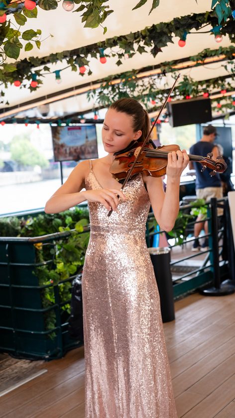 Violinist in a sequinned dress playing on the deck