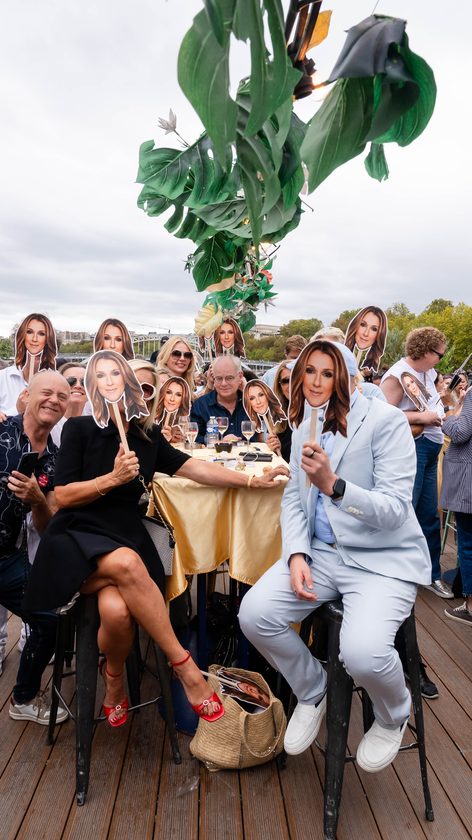 The crowd holding up Céline masks around a table